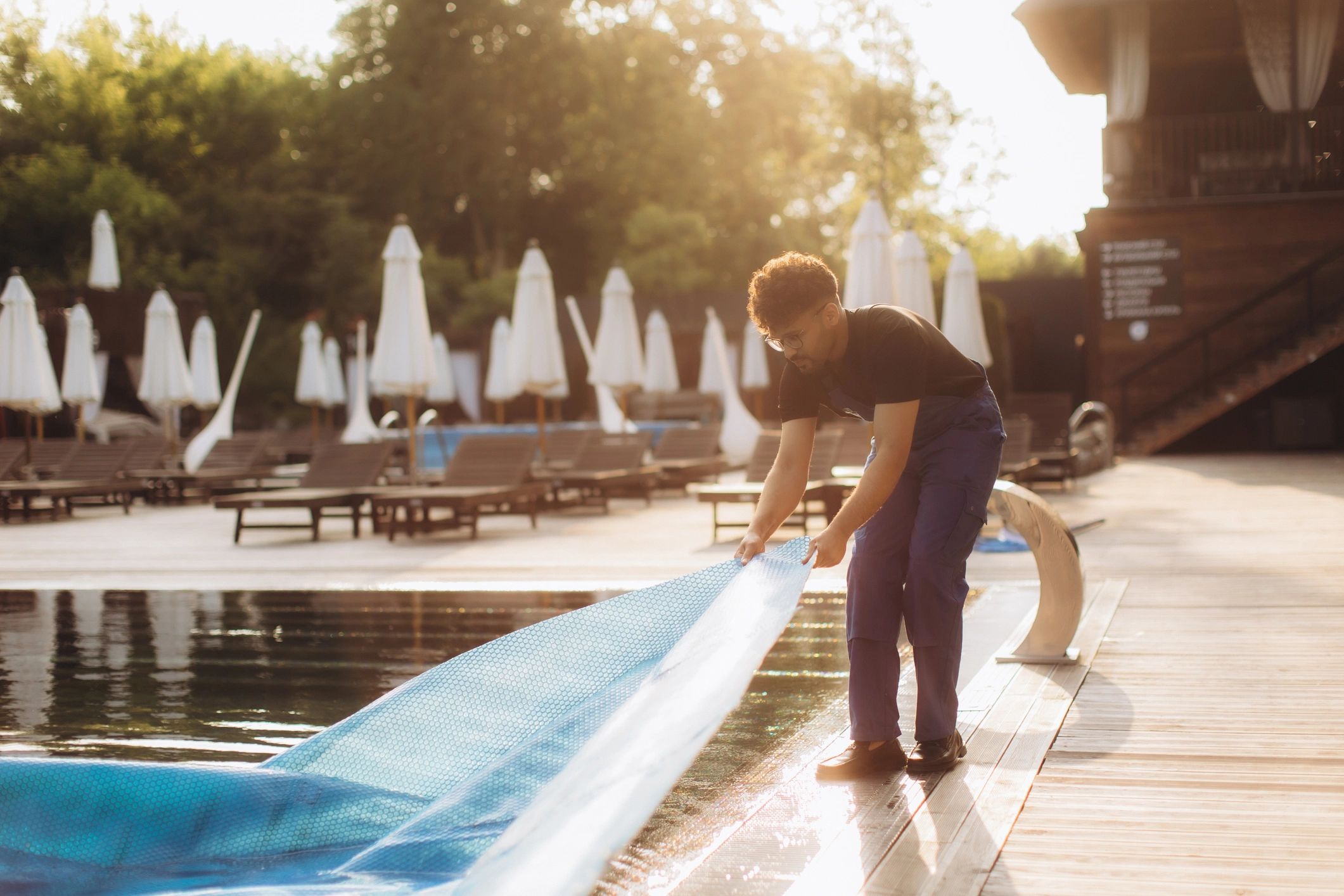 Pool maintenance worker removing a solar cover